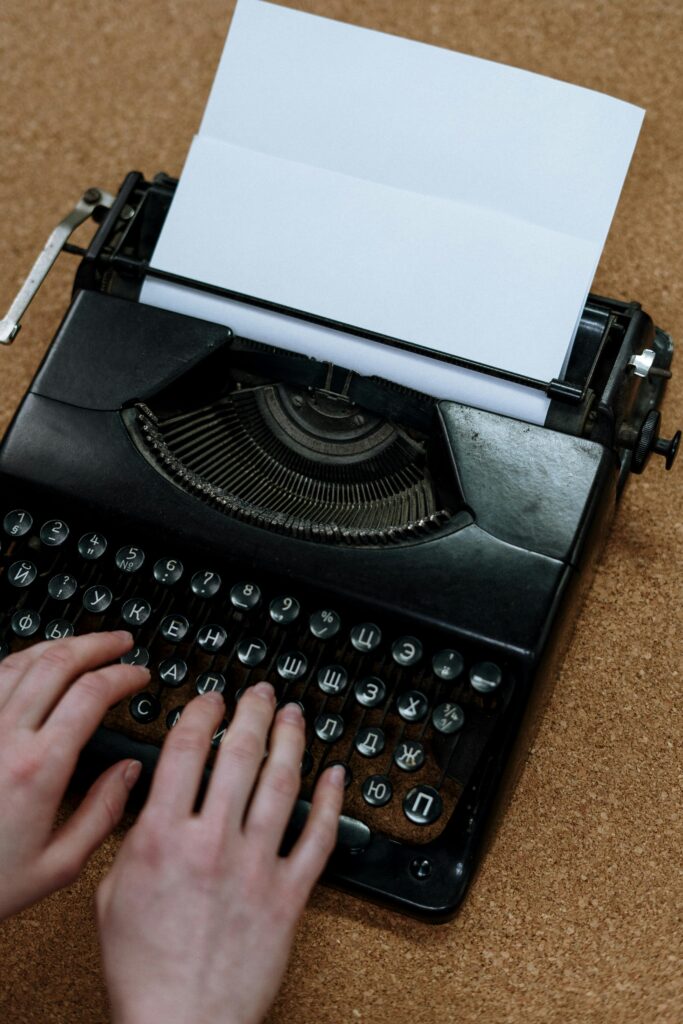 Close-up of hands typing on a vintage typewriter placed on a corkboard. Classic and retro vibes.