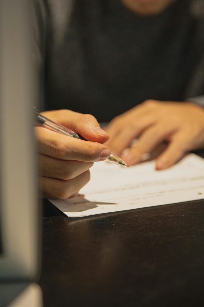 A person writing on a document at an office desk, focused on paperwork.